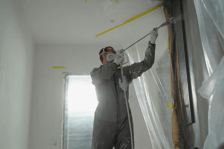 a man standing on a ladder in a room, an airbrush painting, action painting, grey rubber undersuit, worksafe. cinematic, profile image, ceilings