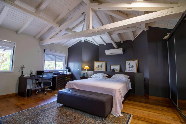 a bed sitting inside of a bedroom on top of a hard wood floor, inspired by Ramon Pichot, unsplash, of augean stables, são paulo, peaked wooden roofs, charcoal and silver color scheme