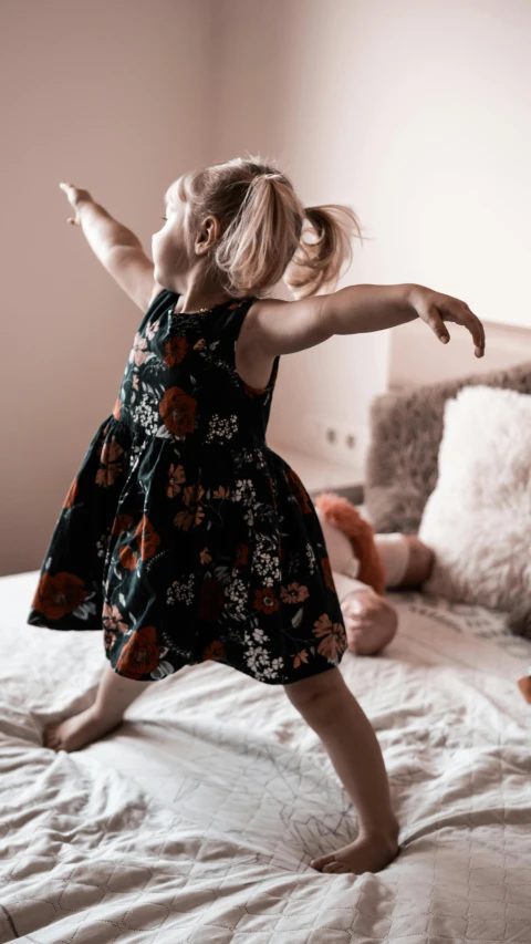 a little girl jumping on top of a bed, inspired by Sophia Beale, pexels contest winner, arabesque, wearing a dark dress, print ready, press shot, toys