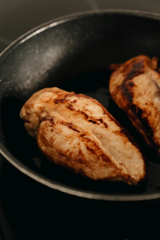 two pieces of chicken cooking in a frying pan, by Daniel Lieske, pexels, maple syrup highlights, 3 / 4 wide shot, thumbnail, side