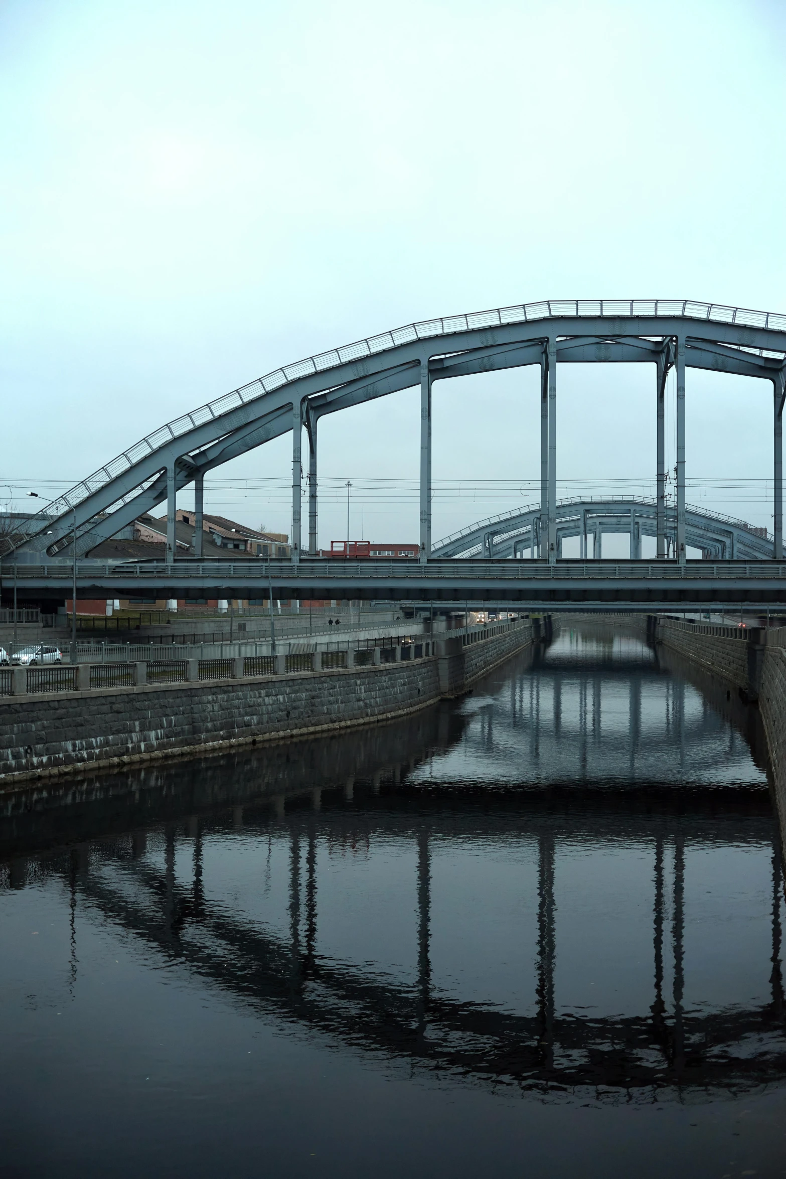 a bridge over a body of water under a cloudy sky, bauhaus, a ghetto in germany, sweeping arches, neo norilsk, glass and steel