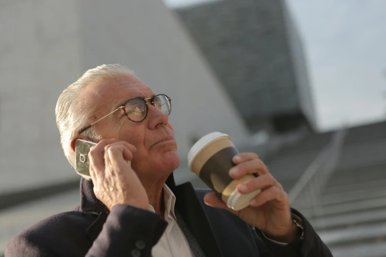 a man talking on a cell phone while holding a cup of coffee, a photo, white-haired, melbourne, profile image, multiple stories