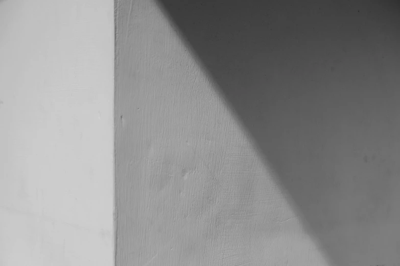 a black and white photo of a corner of a building, a black and white photo, inspired by Arnold Newman, unsplash, postminimalism, sun and shadow, paint texture, single ray of moon, white background wall