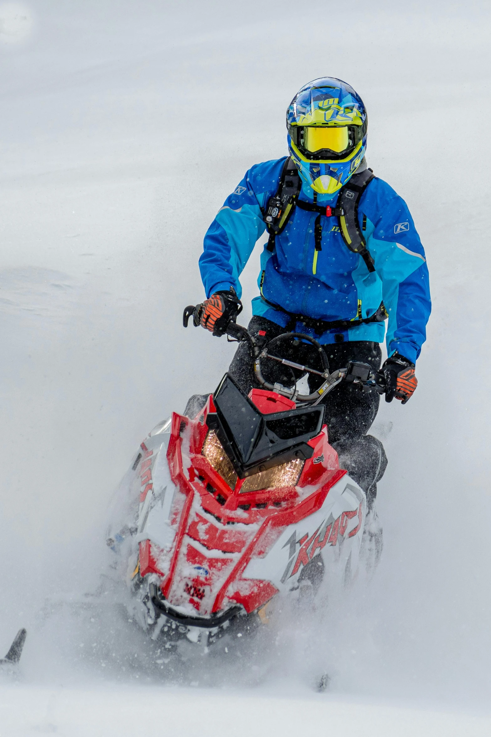 a person riding a snowmobile in the snow, by Paul Emmert, intense colours, avatar image, high quality photo, peaks