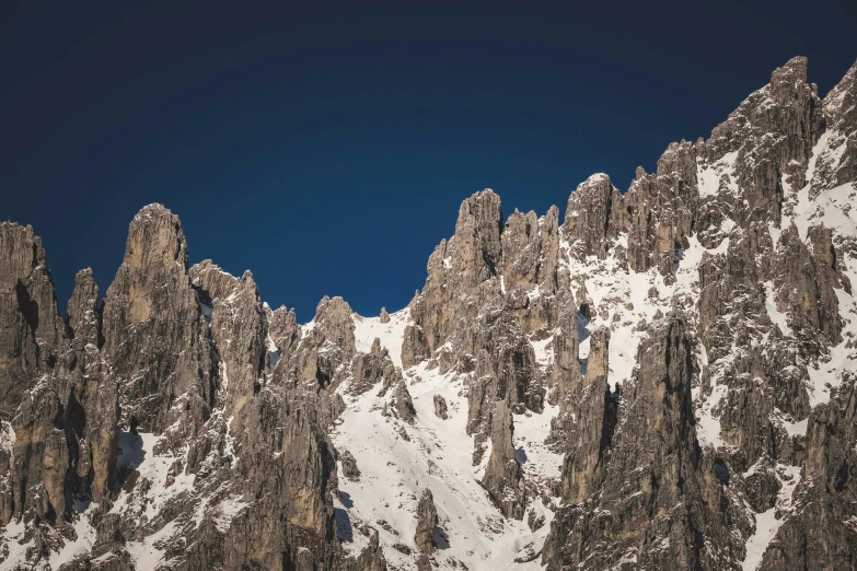 a group of mountains covered in snow under a blue sky, an album cover, by Matthias Weischer, pexels contest winner, tall stone spires, rugged face, grey, texture