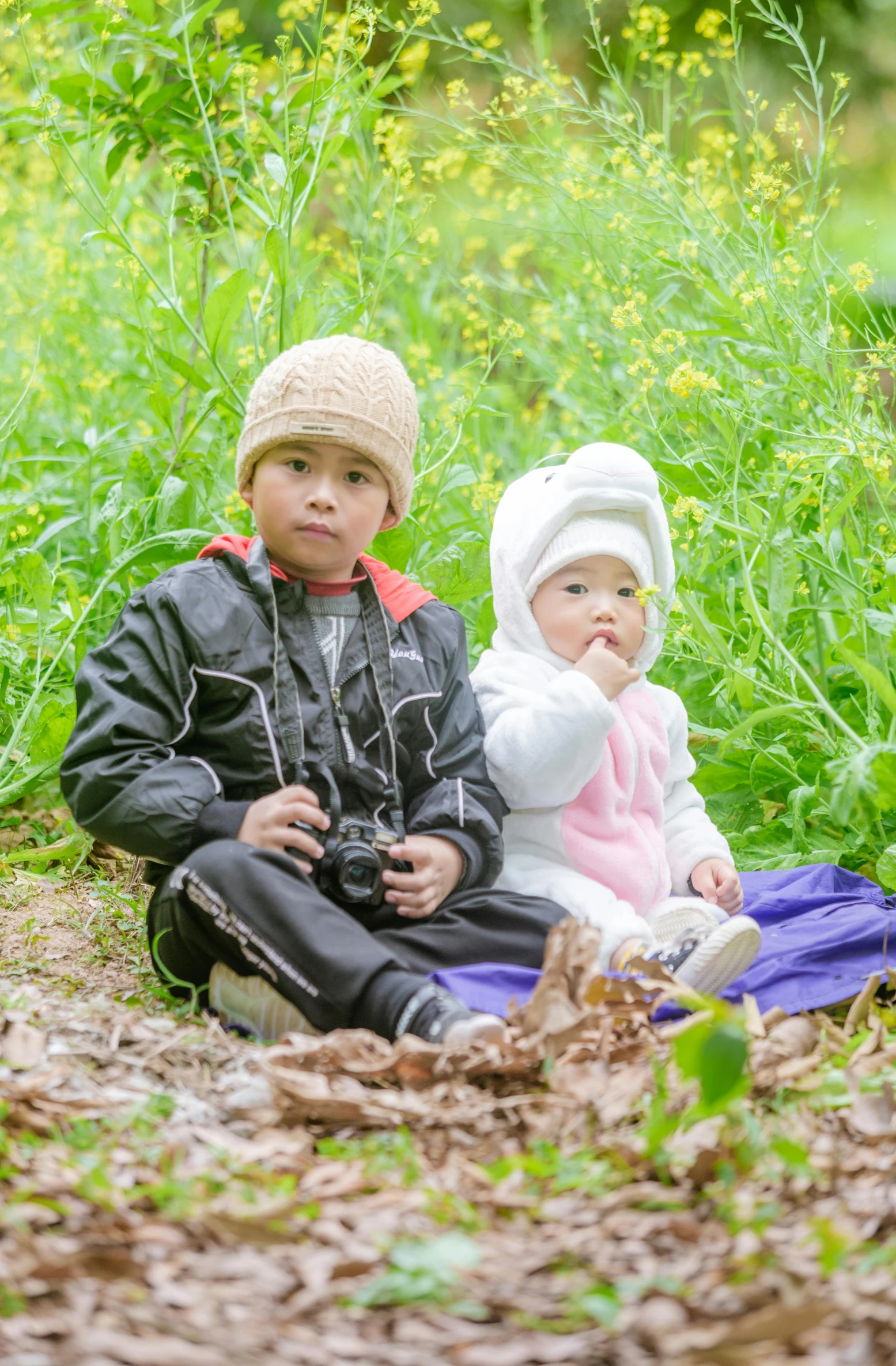 a couple of kids that are sitting in the grass, photograph captured in a forest, leng jun, slide show, low quality photo