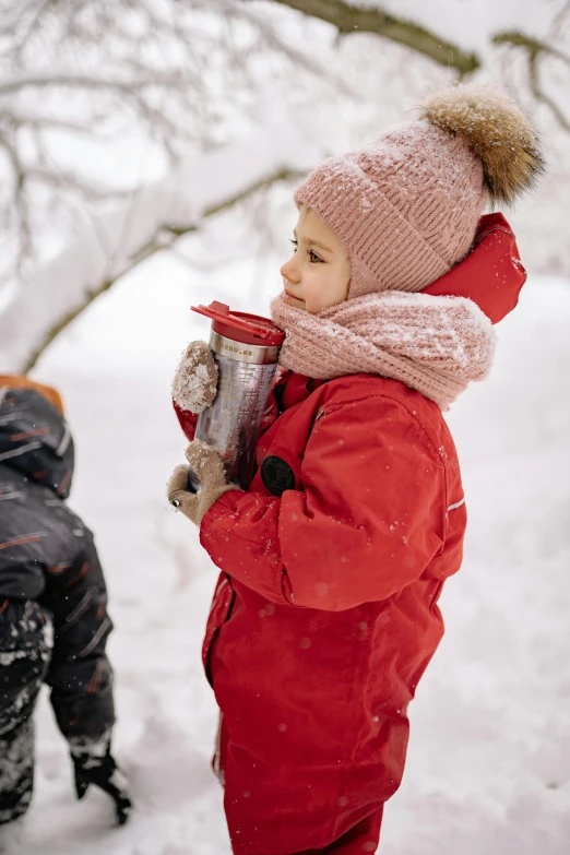 a couple of kids that are standing in the snow, inspired by Elsa Beskow, pexels contest winner, holding a drink, action shot girl in parka, red hat, promotional image