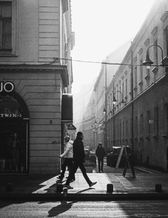 a black and white photo of people walking down a street, a black and white photo, by Kristian Kreković, viennese actionism, morning golden hour, cinematic. by leng jun, tourist photo