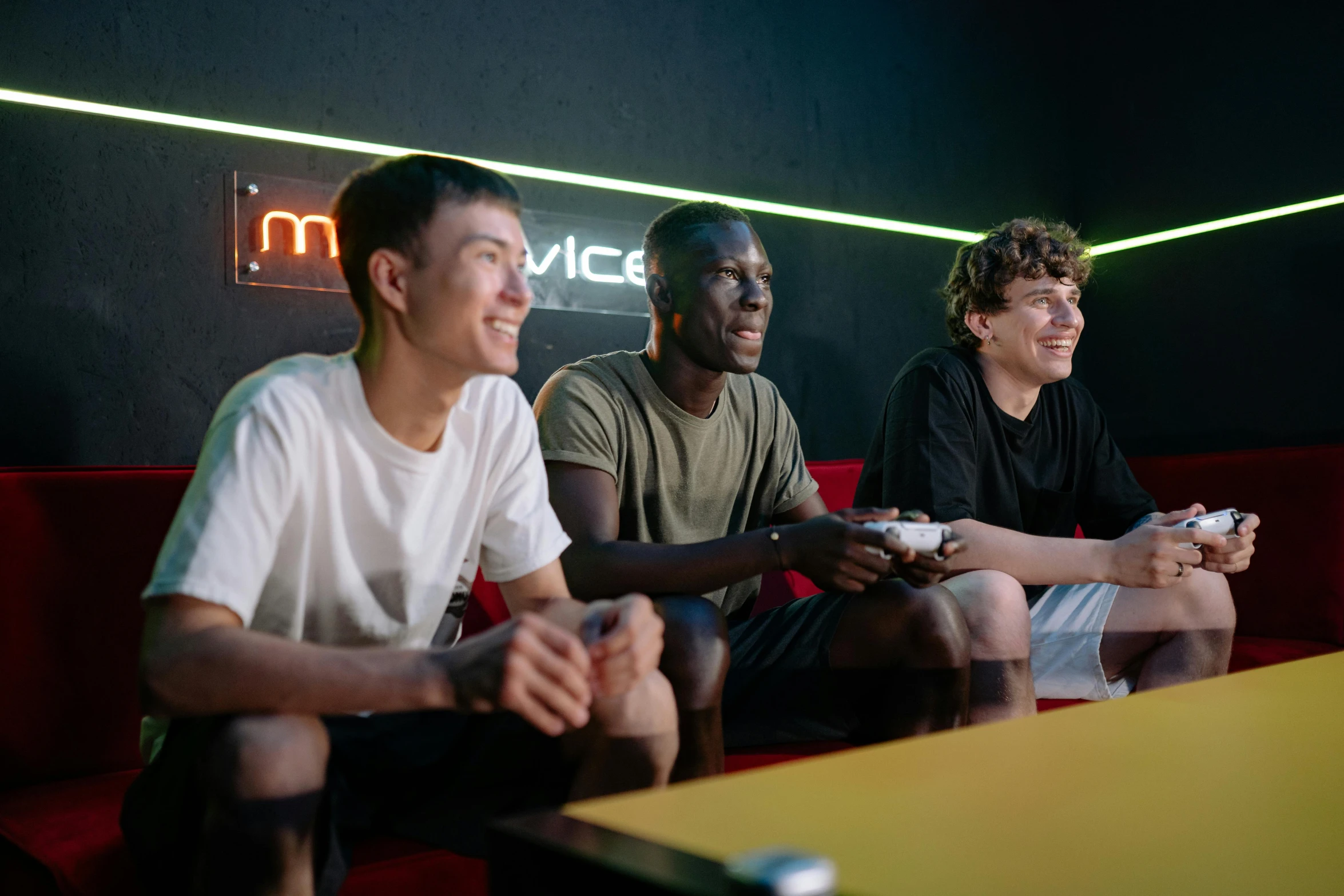 a group of young men sitting on top of a red couch, a cartoon, by Matija Jama, pexels contest winner, renaissance, gaming room, mpc, digital pong screen, 3 actors on stage