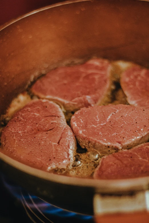 a pan filled with meat cooking on top of a stove, by Jan Tengnagel, unsplash, mutton chops, bottom body close up, liquid gold, game ready