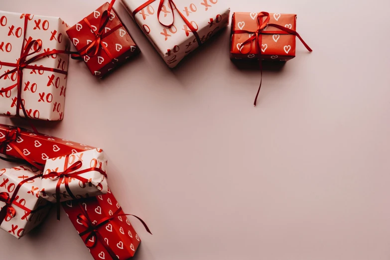 a group of presents wrapped in red and white paper, by Emma Andijewska, trending on pexels, graffiti, pink background, background image, romantic lead, 1 4 9 3