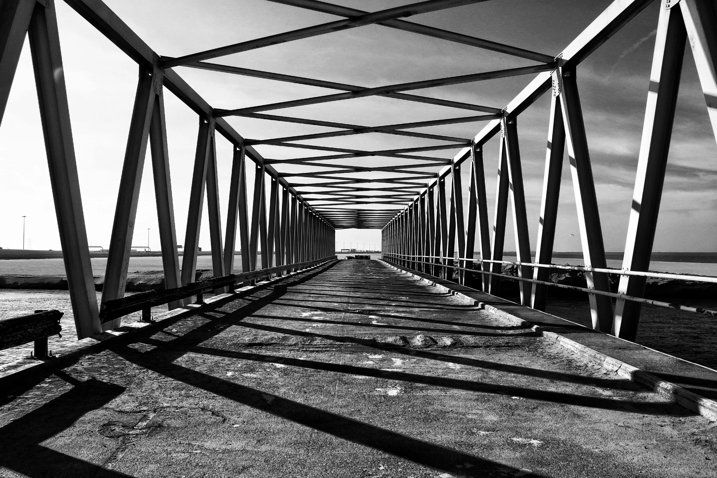 a black and white photo of a bridge, a black and white photo, pexels, op art, hard light and long shadows, symmetry!! full shot!!, rusty, horizon