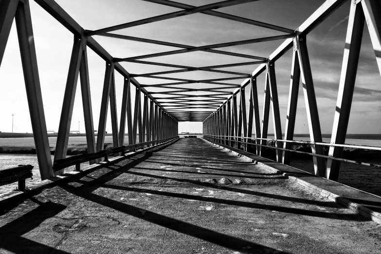 a black and white photo of a bridge, a black and white photo, pexels, op art, hard light and long shadows, symmetry!! full shot!!, rusty, horizon