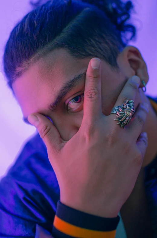 a close up of a person with a ring on their finger, an album cover, by artist, trending on pexels, purple colored eyes, man sitting facing away, young spanish man, big claws