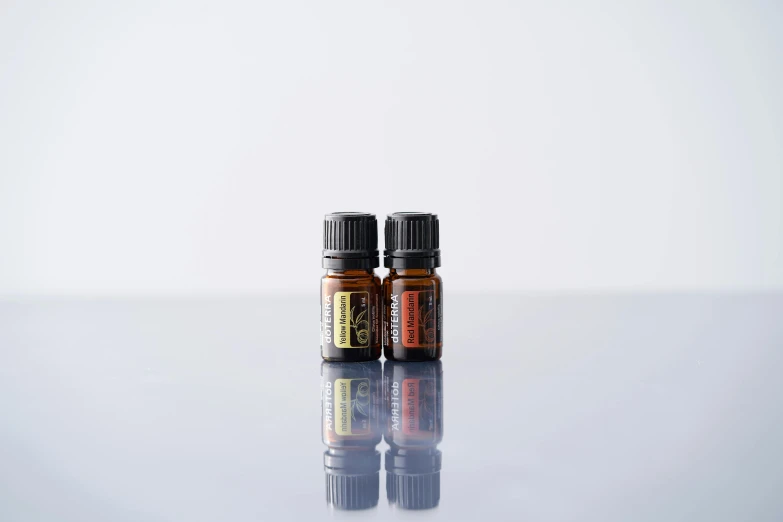 two bottles of essential oils sitting on a table, unsplash, black and orange colour palette, bottom - view, shot on sony a 7, plain background