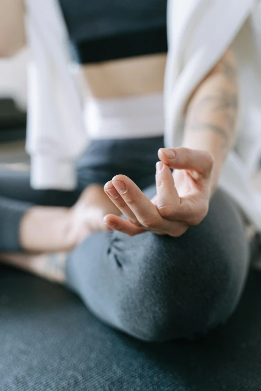 a woman sitting on the floor doing yoga, by Carey Morris, trending on pexels, sits on a finger, magnesium, grey, with index finger