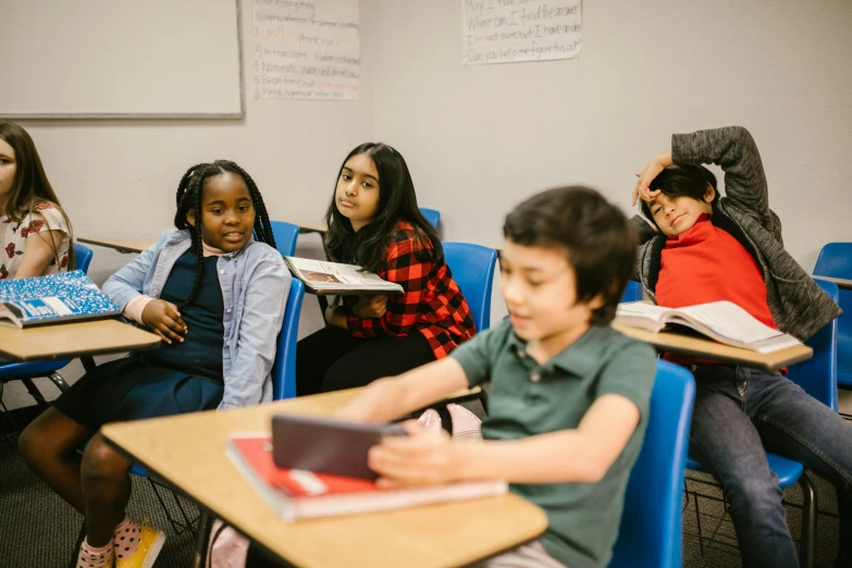 a group of children sitting at desks in a classroom, by Carey Morris, pexels contest winner, fan favorite, looking to the side off camera, diverse, sitting at a desk