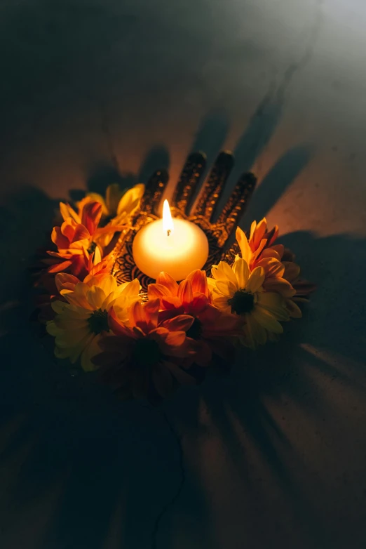 a lit candle surrounded by flowers on a table, hindu aesthetic, fluorescent, light from above, fall season