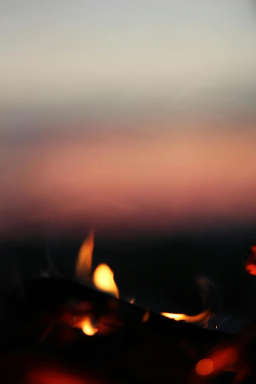 a close up of a person holding a lit candle, fire on the horizon, ((sunset)), dancing around a fire, blurred