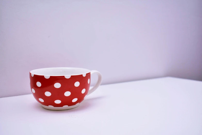 a red and white polka dot cup sitting on a table, unsplash, minimalism, bowl, plain background, coloured