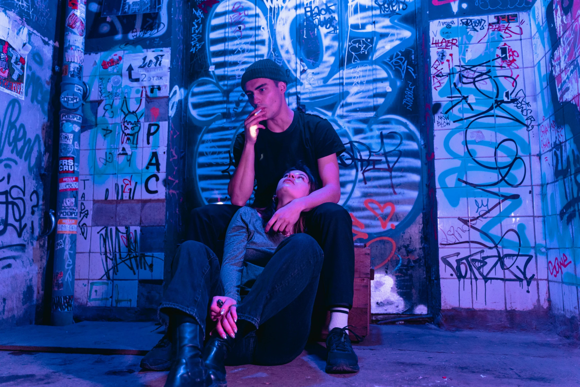 a man sitting in front of a wall covered in graffiti, pexels contest winner, charli bowater and artgeem, perfectly lit. movie still, bisexual lighting, 15081959 21121991 01012000 4k