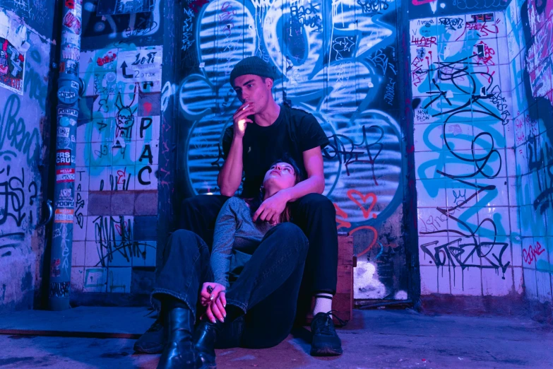 a man sitting in front of a wall covered in graffiti, pexels contest winner, charli bowater and artgeem, perfectly lit. movie still, bisexual lighting, 15081959 21121991 01012000 4k