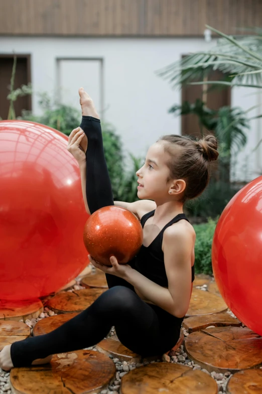 a little girl that is sitting on the ground with some balls, pexels contest winner, arabesque, dynamic stretching, red lanterns, defined muscles, party balloons