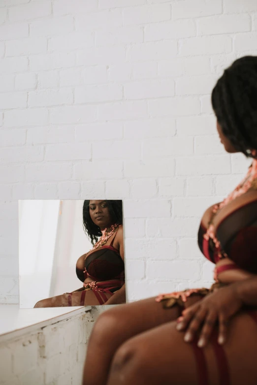 a woman sitting in front of a mirror, an album cover, by Lily Delissa Joseph, trending on pexels, voluptuous body, ( ( dark skin ) ), brown, medium format. soft light