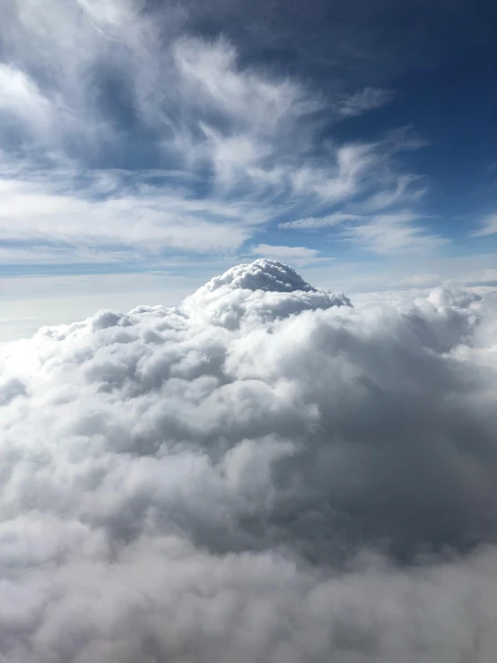 an airplane flying above the clouds with a mountain in the background, unsplash, hurufiyya, towering cumulonimbus clouds, cloud-like white hair, “puffy cloudscape, bird\'s eye view