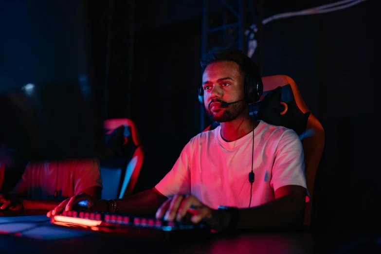 a man sitting at a computer desk with headphones on, a portrait, pexels, esports, background image, (night), high resolution image