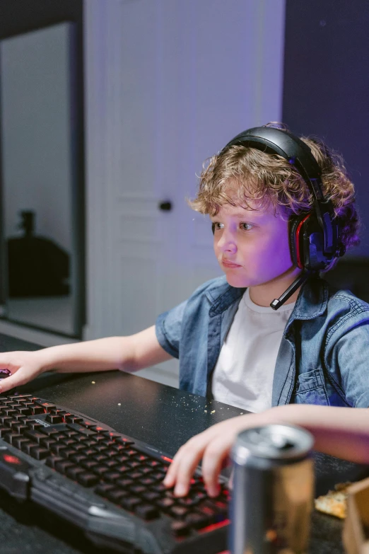 a young boy sitting at a desk with a keyboard and headphones, pexels, wearing a gaming headset, thumbnail, colour corrected, tournament