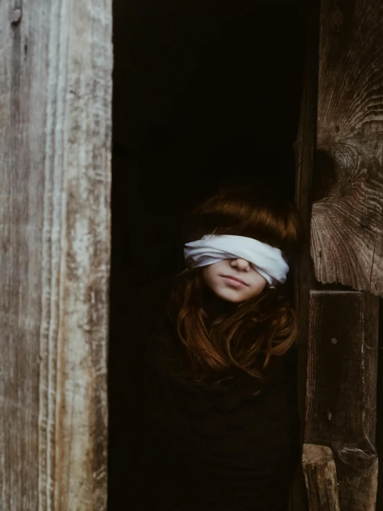 a woman with a blindfold standing in a doorway, inspired by Elsa Bleda, pexels contest winner, renaissance, girl with white eyes, secretly on a village, covered in bandages, young girl