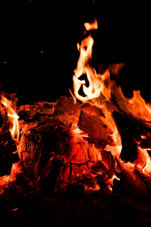 a pile of wood sitting on top of a fire, during the night, profile image