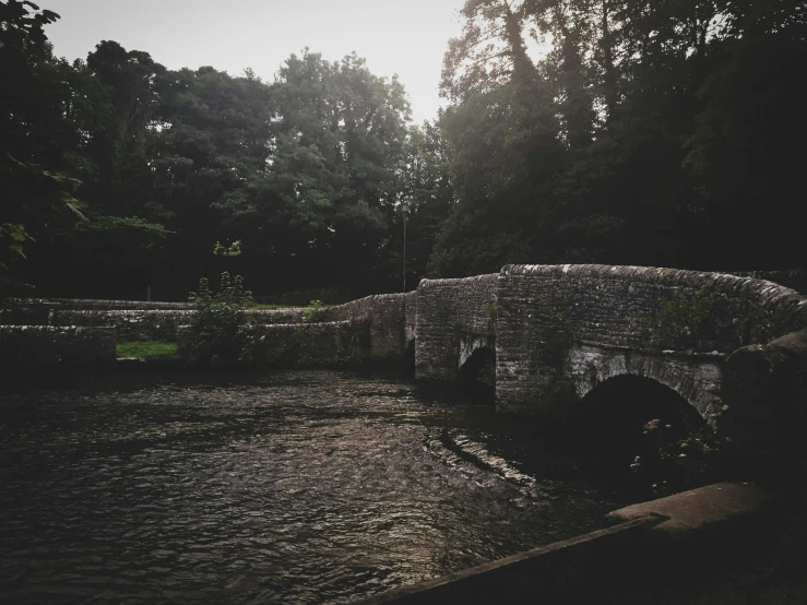 a stone bridge over a river surrounded by trees, unsplash, tonalism, english village, humid evening, 90's photo, phone photo