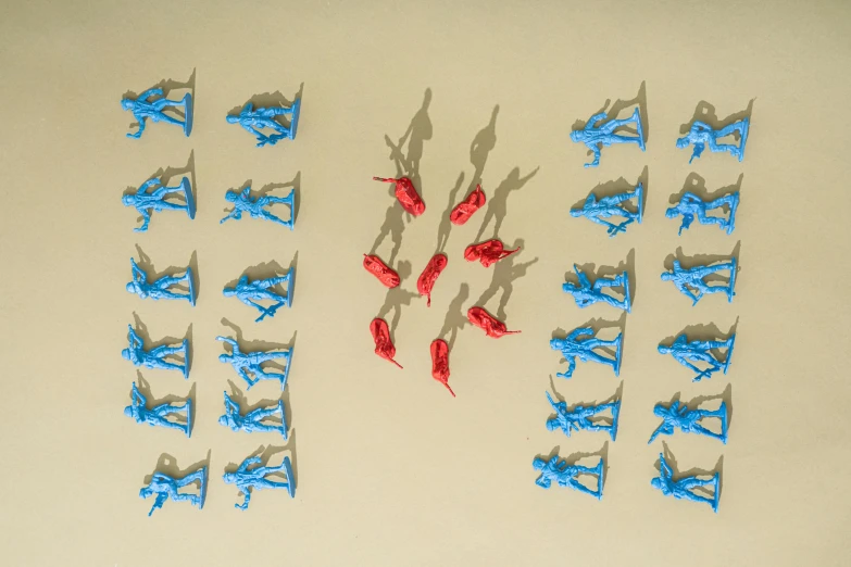 a group of blue and red figurines sitting on top of a table, a high angle shot, war photograph, knolling, plastic