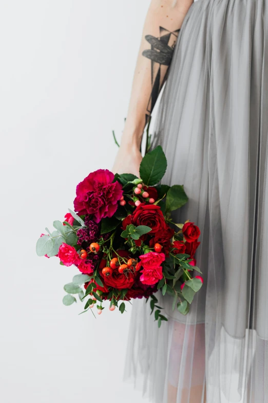 a woman in a gray dress holding a bouquet of flowers, inspired by Pierre-Joseph Redouté, unsplash, romanticism, in crimson red, jewel tones, intricate details. front on, flowy