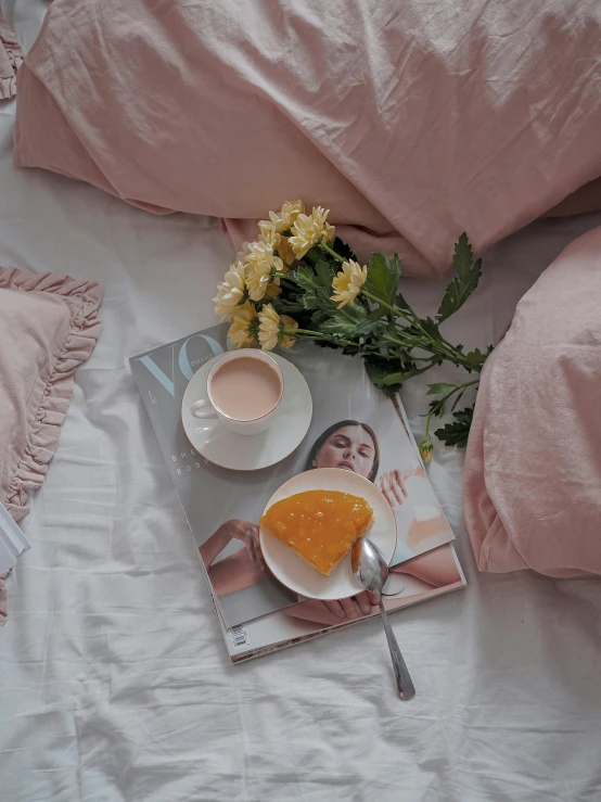 a book sitting on top of a bed next to a cup of coffee, a picture, pastel pink skin tone, vogue cover photo, food, pink and yellow