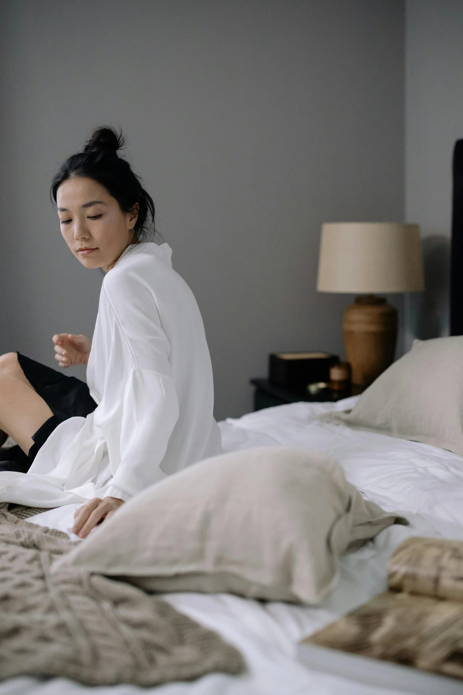 a woman sitting on a bed reading a book, inspired by Li Di, pexels contest winner, minimalism, wearing nanotech honeycomb robe, asian man, gif, knees upturned