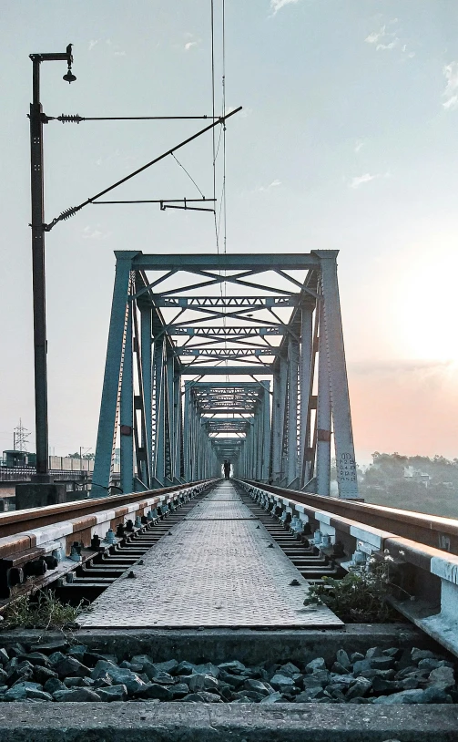 a train track going over a bridge with a sky background, by Bikash Bhattacharjee, unsplash contest winner, panorama view, calcutta, in the morning light, 2000s photo