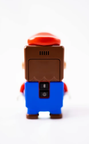 a close up of a toy on a white surface, inspired by Mario Comensoli, unsplash, low - angle shot from behind, brown red blue, minifigure, full body profile camera shot