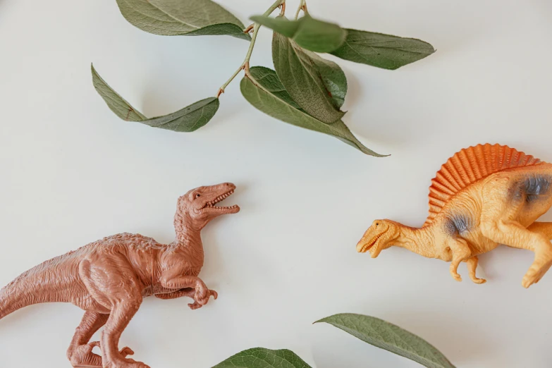 a couple of toy dinosaurs sitting on top of a table, inspired by Adam Rex, trending on pexels, flatlay, terracotta, animals running along, next to a plant