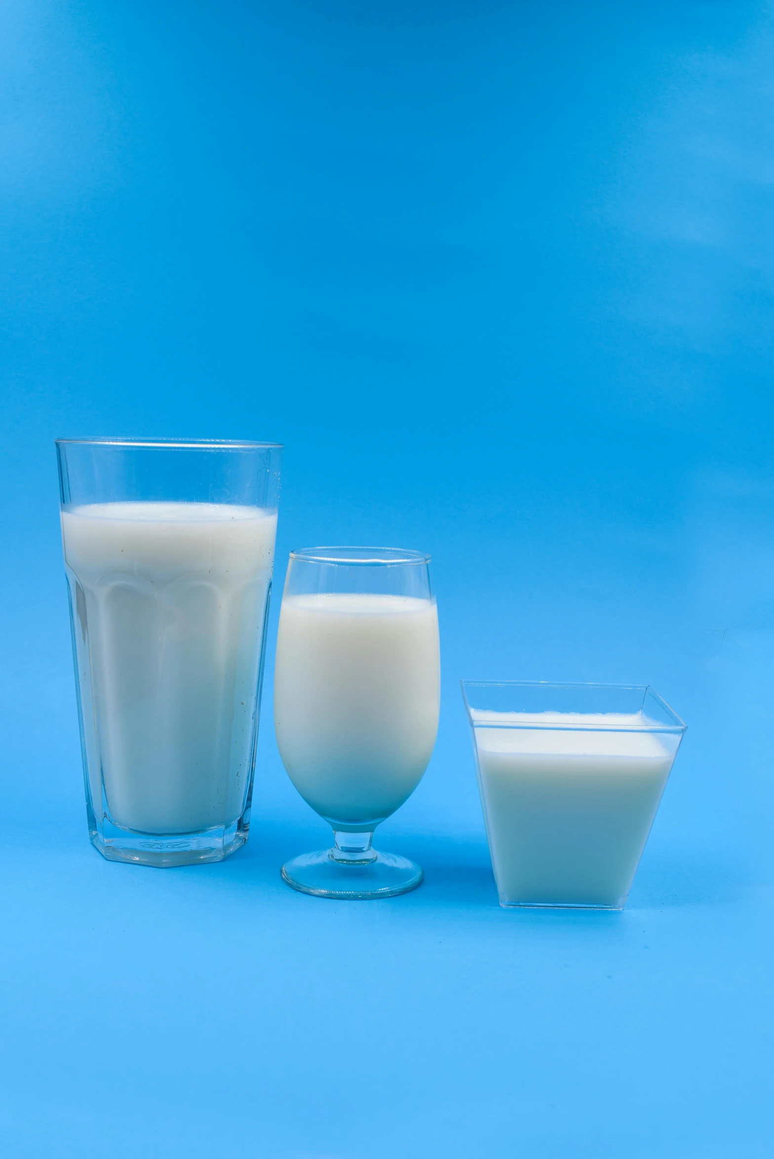 a glass of milk and two glasses of milk on a blue background, by Greg Rutkowski, dau-al-set, large shot, square, silicone skin, farming