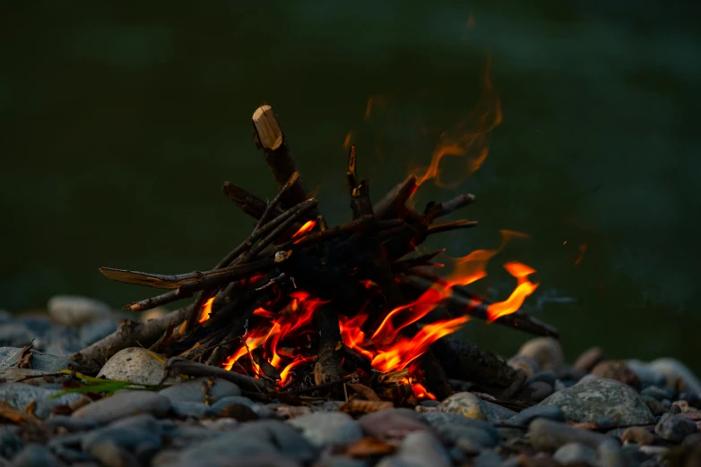 a fire sitting on top of a pile of rocks, pexels contest winner, land art, tiny sticks, melting into rivers, camping, digital still