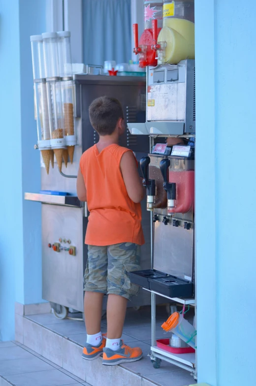 a little boy that is standing in front of a refrigerator, food court, varadero beach, coffee machine, outside