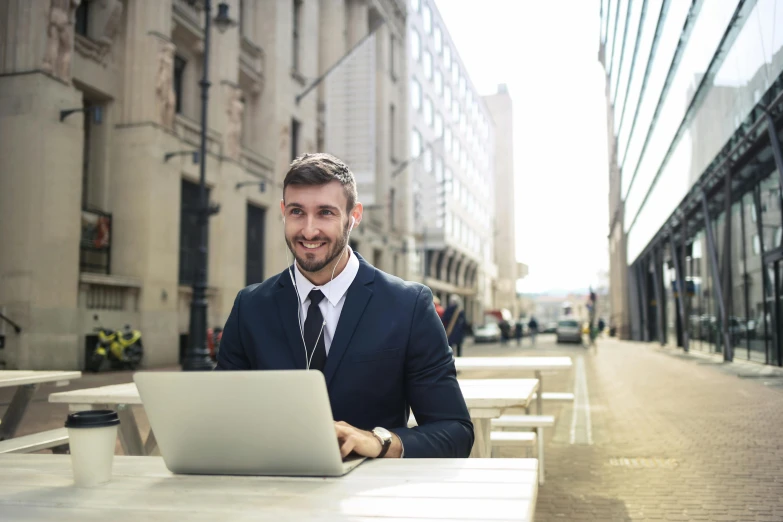 a man sitting at a table with a laptop, pexels contest winner, formal attire, street level, smiling with confidence, avatar image