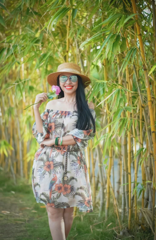 a woman in a dress and hat standing in front of bamboo trees, a picture, inspired by Gina Pellón, pexels, with sunglass, with flowers, full body image, portait photo profile picture