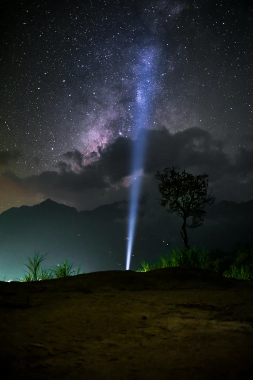 a person standing on top of a hill under a sky filled with stars, by Daren Bader, light and space, laos, search lights, lightening tree, dramatic light 8 k