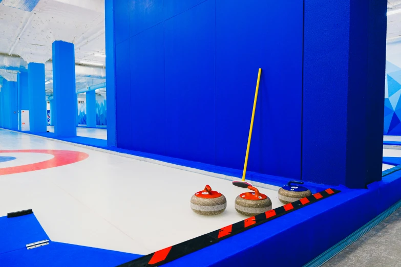 a group of curling stones sitting on top of an ice rink, blue and white colour scheme, indoor picture, thumbnail, spacious