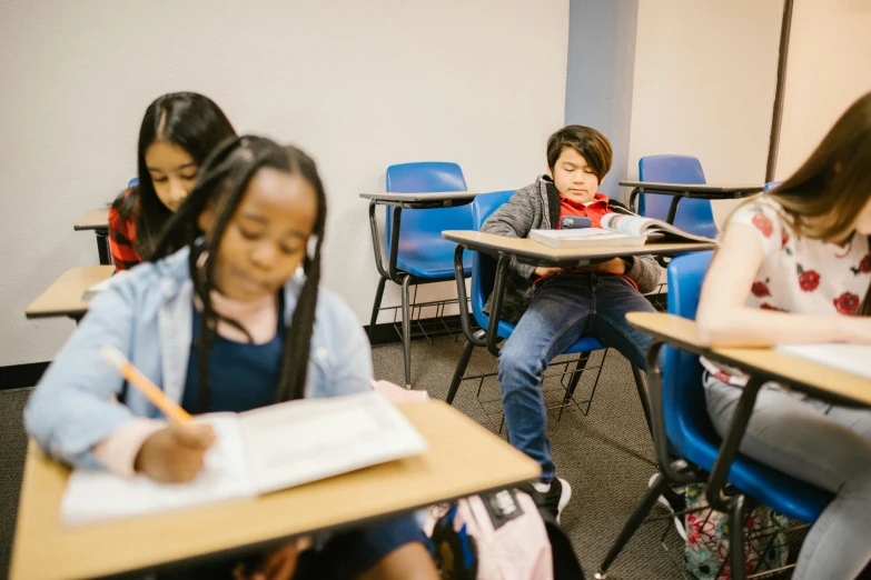a group of children sitting at desks in a classroom, by Carey Morris, pexels contest winner, fan favorite, looking to his left, sitting at a desk, boy and girl are the focus