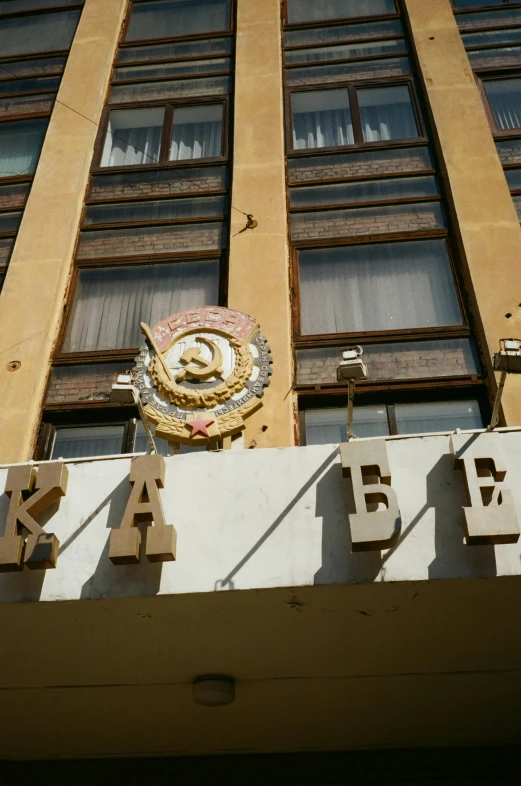 a sign that is on the side of a building, inspired by Otakar Kubín, socialist realism, hotel, military insignia, gold, kasai